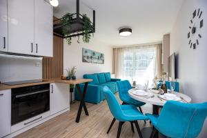 une cuisine et une salle à manger avec une table et des chaises bleues dans l'établissement GIL APARTMENTs 14, à Cracovie
