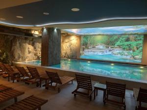 a swimming pool with chairs and a large aquarium at Tesoro apartmani Spa&Wellness in Zlatibor