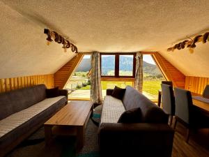 een woonkamer met banken, een tafel en ramen bij Holiday home Kraljica in Vlasic