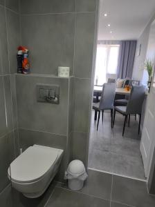 a bathroom with a toilet and a dining room at Apartament U Bosmana in Dźwirzyno
