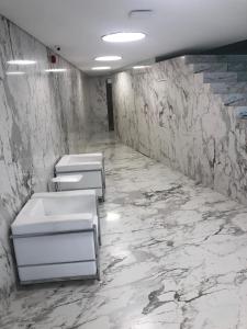 Baño con 3 lavabos y paredes de mármol en Apart Lola en Buenos Aires
