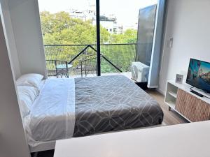 um quarto com uma cama e uma varanda com uma televisão em Apart Lola em Buenos Aires