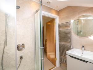 ein Badezimmer mit Dusche, Waschbecken und Spiegel in der Unterkunft Rowanberry Cottage in Grasmere + 24 Fotos