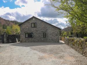 a stone house on a gravel driveway at Rowanberry Cottage in Grasmere