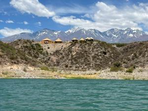 een groep huizen op een heuvel naast een waterlichaam bij Bello depto en la nieve Juncal in Los Penitentes