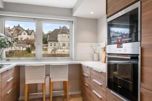 a kitchen with a counter with two chairs and a window at Scandinavian Style Apartement! Balcony and Stunning Views! in Bergen