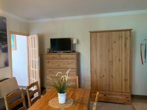 a living room with a table and a tv and a wooden cabinet at Sosnowa Mila in Pobierowo