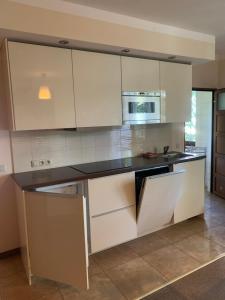 a kitchen with white cabinets and a black counter top at Sosnowa Mila in Pobierowo