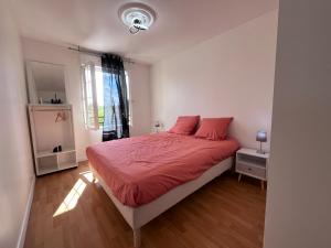 Schlafzimmer mit einem Bett mit roter Bettwäsche und einem Fenster in der Unterkunft Maison de Caractère à Ballainvilliers in Ballainvilliers