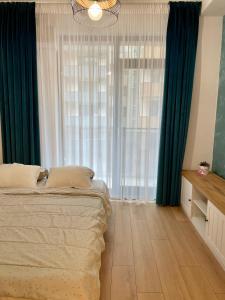 - une chambre avec un lit et une grande fenêtre dans l'établissement Seaside Apartments Mamaia Nord, à Mamaia Nord – Năvodari