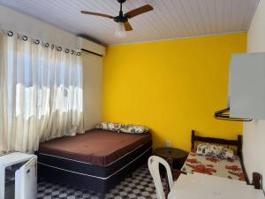 a bedroom with a bed and a yellow wall at Suites do Rafa Ubatuba in Ubatuba