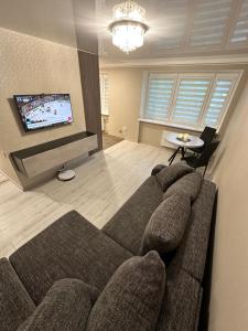 een woonkamer met een bank en een flatscreen-tv bij Rasa Apartment in Jelgava