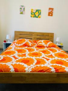 uma cama com um edredão laranja e branco e almofadas em Black em Ensisheim