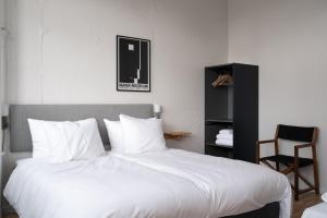 a bedroom with a large bed with white sheets and a chair at Beach Trail apartments by Daniel&Jacob's in Copenhagen