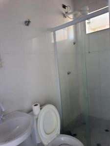 a white bathroom with a toilet and a sink at Suites do Rafa Ubatuba in Ubatuba