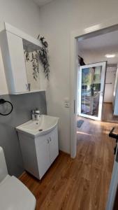 a white bathroom with a sink and a hallway at Unatime.Krupa in Bosanska Krupa