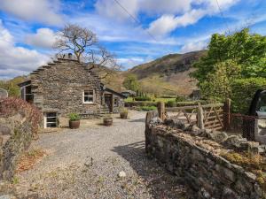 a stone house with a stone wall and a fence at Beckside Studio in Patterdale