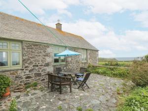 a stone cottage with a table and chairs and an umbrella at Parc An Castle Cottage in Lizard