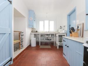 a kitchen with blue cabinets and a red tile floor at Parc An Castle Cottage in Lizard