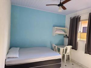 a small room with a bed and a table at Suites do Rafa Ubatuba in Ubatuba