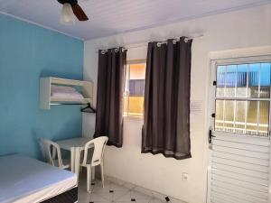 a room with a bed and a table and a window at Suites do Rafa Ubatuba in Ubatuba