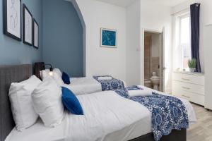 2 Betten in einem Schlafzimmer mit blau und weiß in der Unterkunft Air Host and Stay - Spacious 5-Bed Retreat in Edge Grove Sleeps 9 in Liverpool