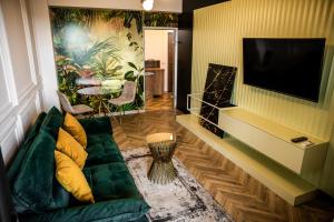 ein Wohnzimmer mit einem grünen Sofa und einem Flachbild-TV in der Unterkunft Amazing Apartment - Palas Mall in Iaşi