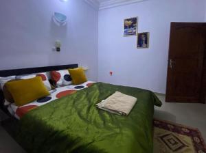 1 dormitorio con 1 cama con sábanas verdes y almohadas amarillas en SereneLux Home, en Cotonou