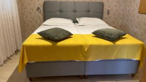 ein Bett mit einer gelben Decke und zwei Kissen darauf in der Unterkunft Apartmani Slavonija in Orebić