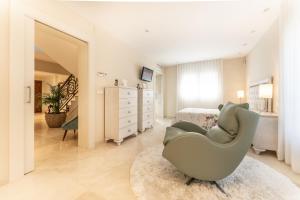 een witte slaapkamer met een grijze stoel voor een bed bij Villa Stella Maris Luxury 4BR Pool Beach in Roda de Bará