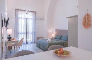 Mediterranea Residence في ناردو: غرفة نوم بسرير وطاولة مع صحن من الفواكه