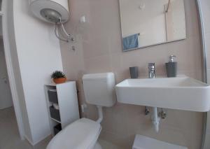 a white bathroom with a toilet and a sink at Studio M in Pula +15 photos