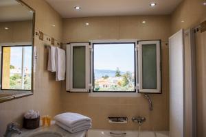 a bathroom with a tub and a sink and two windows at The Garden House in Aegina Town