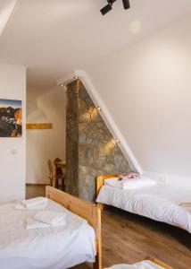 a room with two beds and a stone wall at Villa Szarotka in Dzianisz