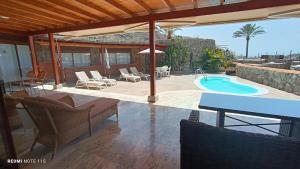 a patio with a pool and chairs and a table at ANFI TOPAZ VILLA TAURO GOLF private pool in Mogán