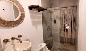 ein Bad mit einer Dusche, einem Waschbecken und einem Spiegel in der Unterkunft Pakáal Muliix - Limóm in Mérida