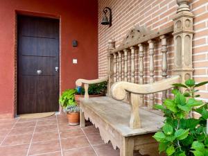 un banco de madera sentado fuera de una casa con una puerta en Casa Miragredos, a solo 5 min de Puy du Fou y Toledo, en Cobisa