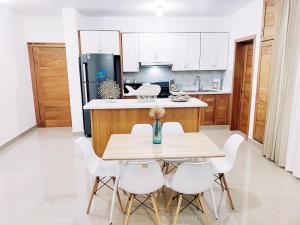 uma cozinha com uma mesa de madeira e cadeiras brancas em Confortable Apartamento con Piscina en Cabrera em Cabrera
