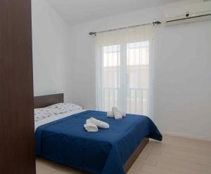 ein Schlafzimmer mit einem blauen Bett und Handtüchern darauf in der Unterkunft Cape Kamenjak Apartments in Premantura in Premantura