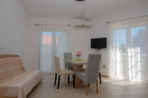 Zimmer mit einem Tisch, Stühlen und einem TV in der Unterkunft Cape Kamenjak Apartments in Premantura in Premantura