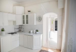 利沃夫Світла затишна квартира в центрі біля Оперного театру з балконом, який виходить у тихий львівський дворик的厨房里有白色的橱柜，墙上挂着一个钟