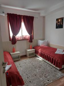 a bedroom with two red beds and a window at VILA ONIX in Săcueni