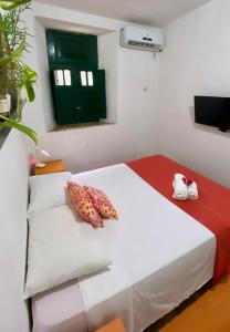 um quarto com uma cama branca e uma janela verde em Casa de Olinda em Olinda