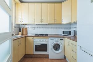 a kitchen with wooden cabinets and a washer and dryer at Urbanización Jardín del Golf 1 in Novo Sancti Petri