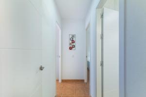 a hallway with white walls and a glass door at Urbanización Jardín del Golf 1 in Novo Sancti Petri