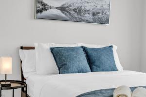 a bedroom with a white bed with blue pillows at Modern Downtown Suites in Toronto