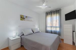 a white bedroom with a bed and a window at Urbanización Jardín del Golf 1 in Novo Sancti Petri