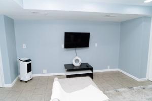 uma sala de estar branca com um sofá branco e uma televisão de ecrã plano em King Bed/ apartment/Free St Parking/ Quiet em Filadélfia