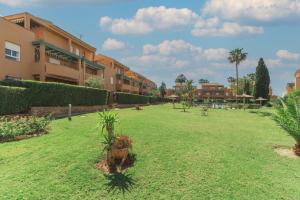 a large yard with palm trees and buildings at Urbanización Jardín del Golf 1 in Novo Sancti Petri