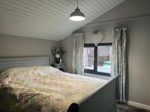 Un dormitorio con una cama grande y una ventana en Stunning 2 Bed Lodge On The Lake, en South Cerney